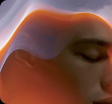 A calm face beneath a flowing warm-toned fabric